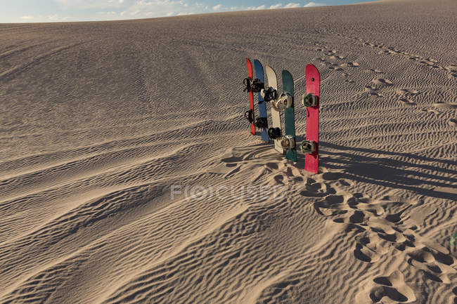 Sandboard mantido em uma fileira na areia em um dia ensolarado — Fotografia de Stock