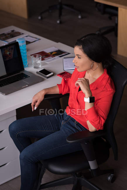 Задумчивая деловая женщина сидит за столом в креативном офисе — стоковое фото
