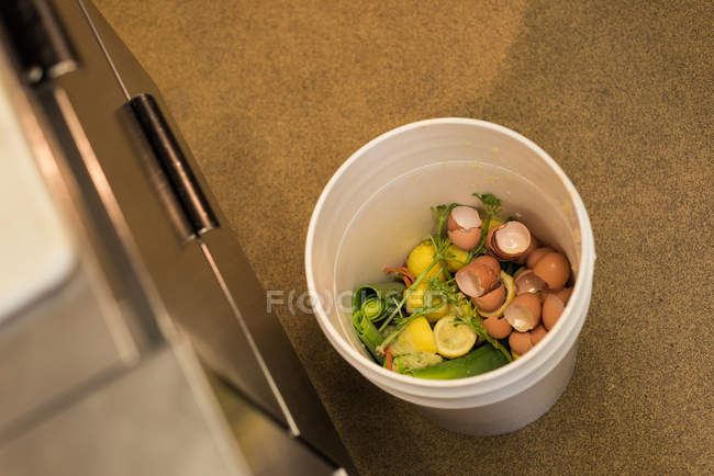 Estanterías de huevos y residuos vegetales en el cubo de basura en la cocina - foto de stock