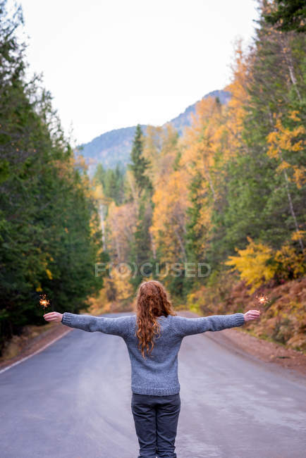 Rear view of woman with arms outstretched standing on road — Stock Photo
