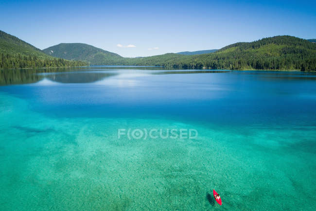 Kayaker kayaking in shallow turquoise water along the coastline on a sunny day — Stock Photo