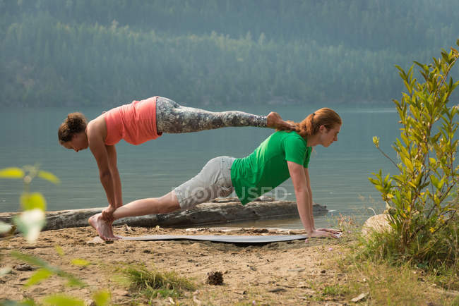 Sportliches Paar praktiziert an einem sonnigen Tag Acroyoga in Küstennähe — Stockfoto