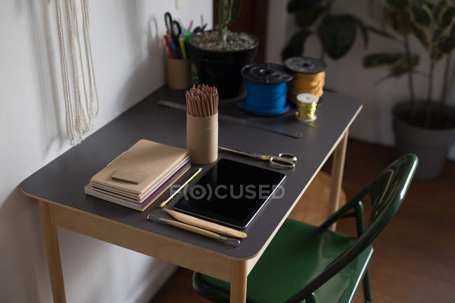 Цифровой планшет и канцелярские принадлежности на столе в мастерской — стоковое фото