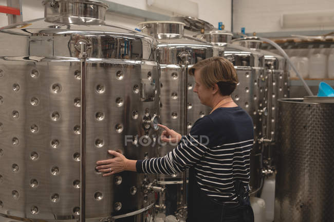 Lavoratrice che controlla un manometro del serbatoio di stoccaggio nella fabbrica di birra — Foto stock