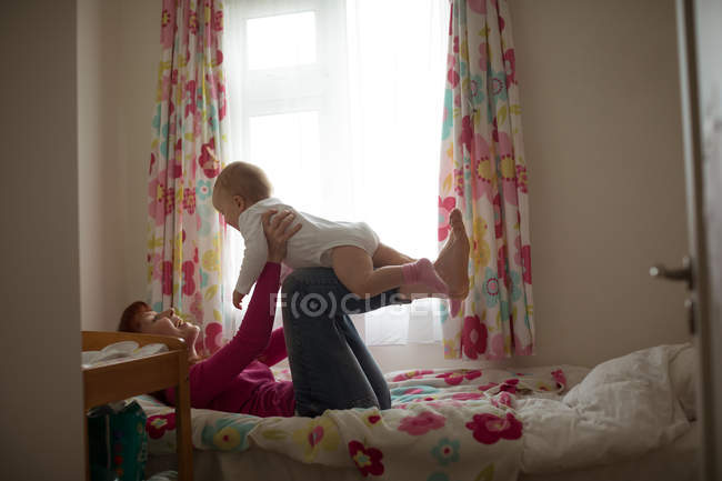 Мать играла со своей маленькой девочкой в спальне дома — стоковое фото