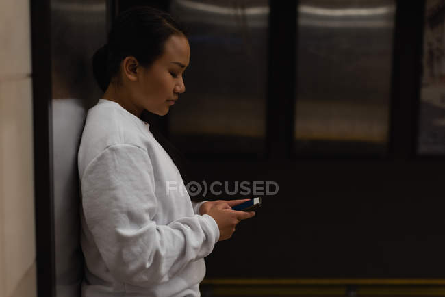 Mulher usando telefone celular na estação subterrânea — Fotografia de Stock