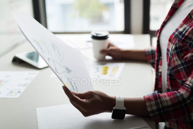 Femme exécutive regardant un document au bureau — Photo de stock