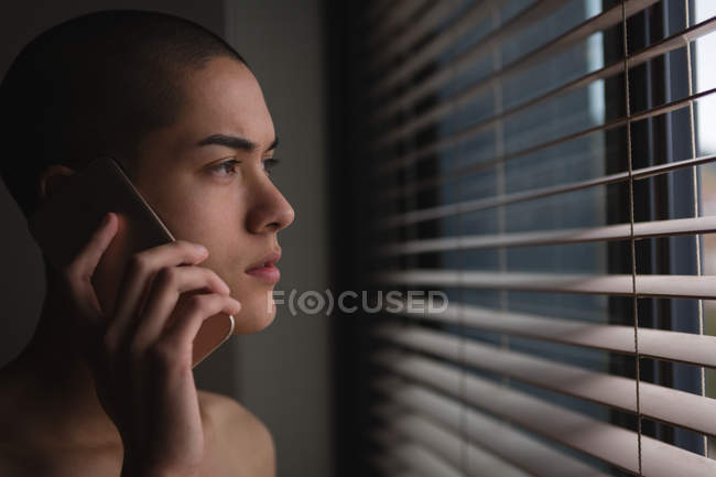 Молодий чоловік, що говорив на мобільному телефоні під час перегляду вікна будинку — стокове фото