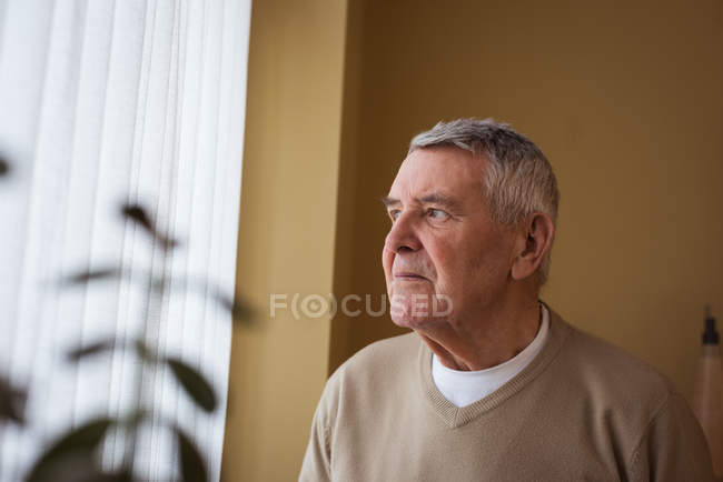 Задумчивый пожилой человек, стоящий в доме престарелых — стоковое фото