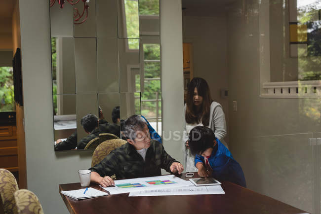 Семья с помощью цифрового планшета с диаграммой дома — стоковое фото
