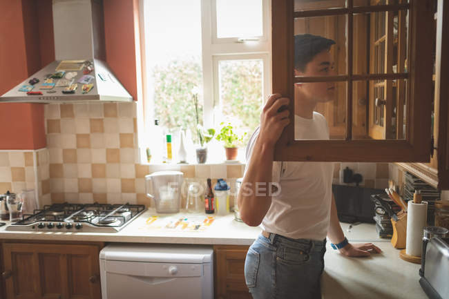 Man looking in kitchen cabinet in home interior. — Stock Photo