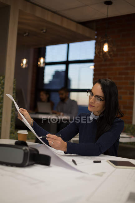 Female looking at blueprint in office — Stock Photo