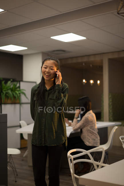 Female executive talking on mobile phone in office — Stock Photo