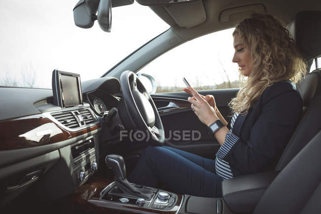Schöne weibliche Führungskraft mit Handy im Auto — Stockfoto