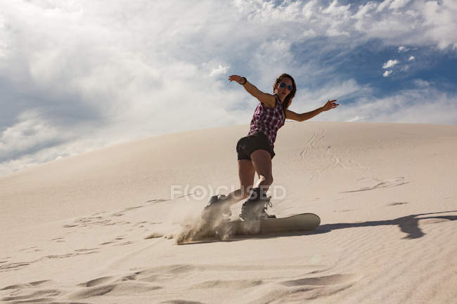 Woman sandboarding on sand dune at desert — Stock Photo