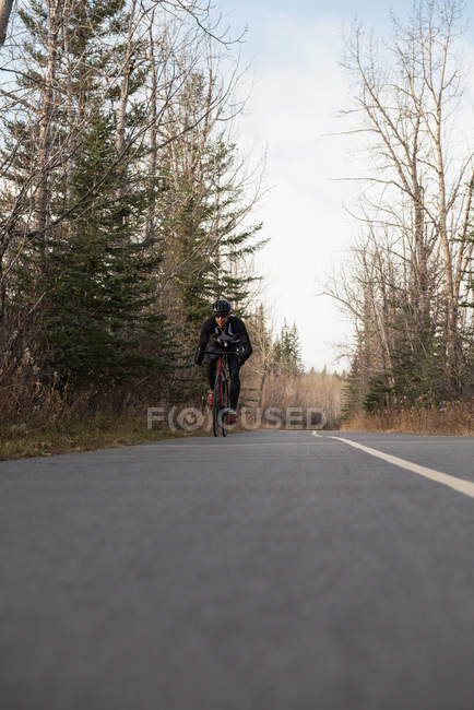 Biker andar de bicicleta de montanha na estrada em um dia ensolarado — Fotografia de Stock