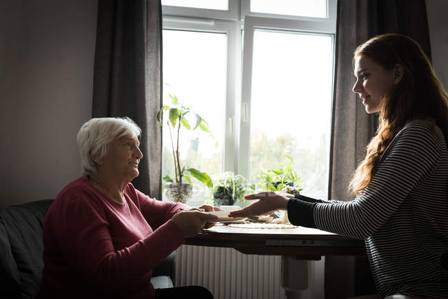 Grandmother receiving breakfast from granddaughter in living room at home — Stock Photo