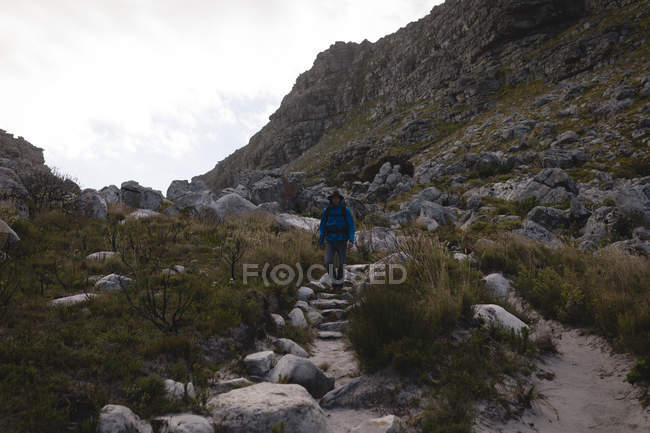 Wanderer geht mit Rucksack auf Felsen hinunter — Stockfoto