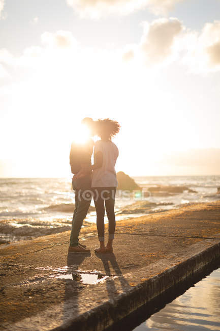Романтична пара стоячи на пристані під час заходу сонця — стокове фото