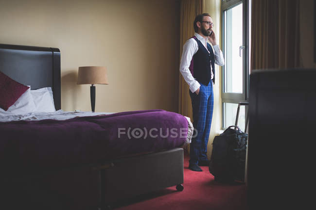 Homme d'affaires parlant sur téléphone portable dans la chambre d'hôtel — Photo de stock