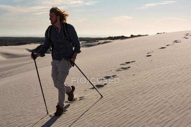 Male hiker with trekking pole walking on sand — Stock Photo
