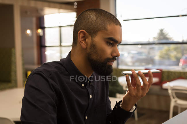 Male executive talking on mobile phone in cafeteria at office — Stock Photo