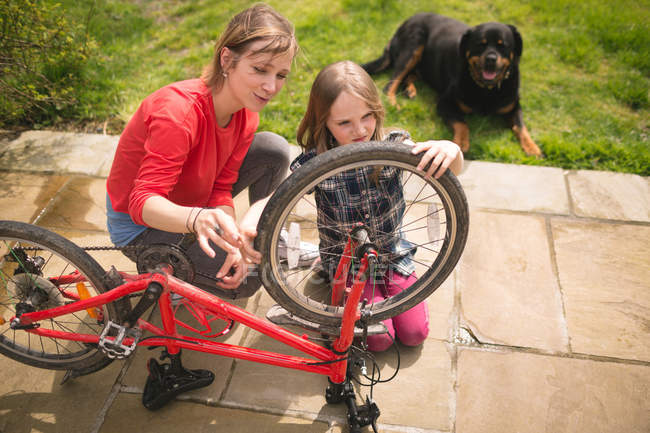 Мать и дочь вместе ремонтируют велосипед на заднем дворе — стоковое фото