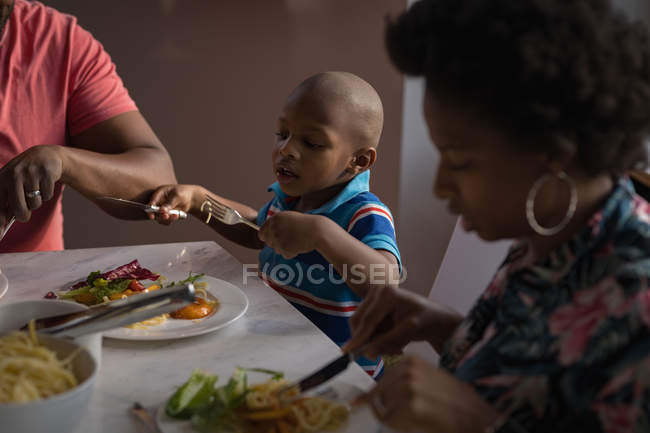 Bambino prescolare con i genitori che mangiano a tavola a casa . — Foto stock
