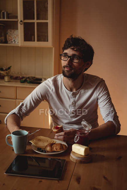 Homme réfléchi prenant le petit déjeuner dans la cuisine à la maison — Photo de stock