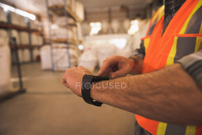 Seção média do homem em vestuário de trabalho de proteção usando smartwatch — Fotografia de Stock