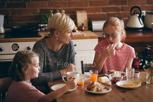 Mother and kids having breakfast at table in kitchen — Stock Photo