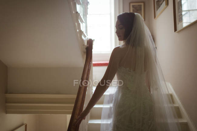 Bride looking sideways while climbing the steps at home — Stock Photo