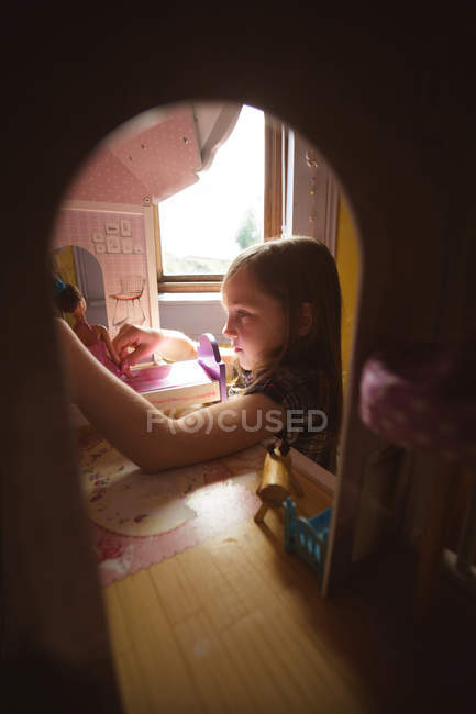 Девушка играет с кукольным домиком в спальне дома — стоковое фото