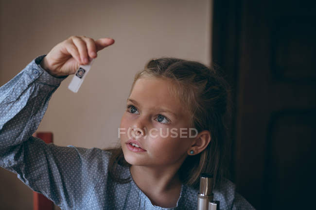 Menina inteligente examinando a corrediça de vidro em casa — Fotografia de Stock