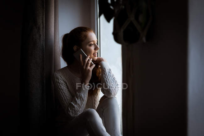 Sonriente adolescente hablando en el teléfono móvil en casa - foto de stock