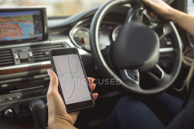 Close-up de executivo do sexo feminino usando telefone celular enquanto dirige um carro — Fotografia de Stock