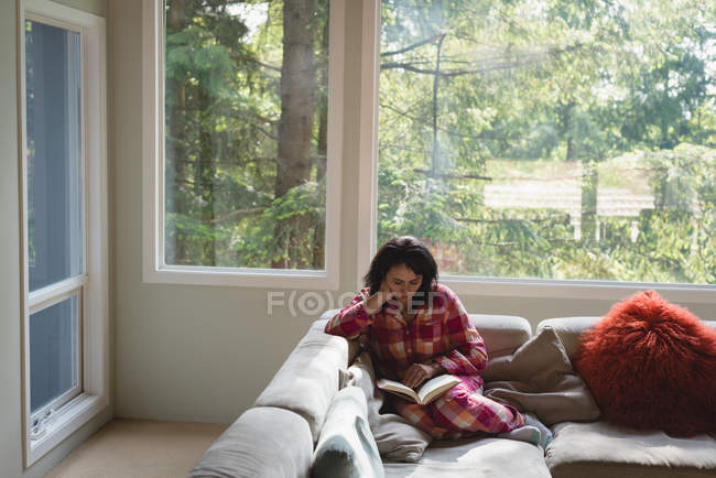 Женщина читает книгу в гостиной — стоковое фото
