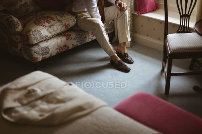 Mid section of groom wearing his shoes at home — Stock Photo