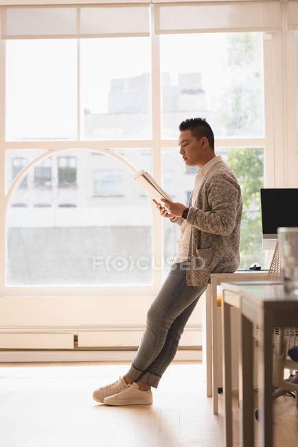 Чоловік керівник сидить на столі читаючи документи в офісі — стокове фото