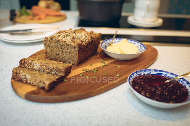 Gros plan des tranches de pain sur la planche en bois dans la cuisine — Photo de stock