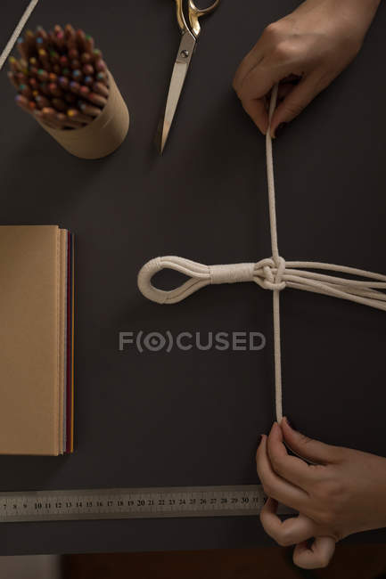 Cropped image of woman knotting strings — Stock Photo