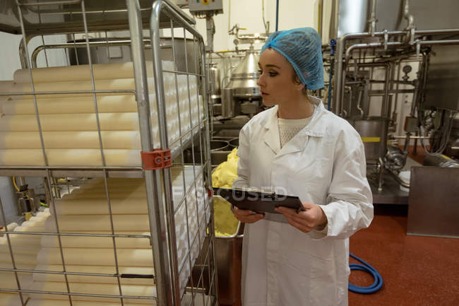 Female worker monitoring the food rolls kept in shelf at factory — Stock Photo