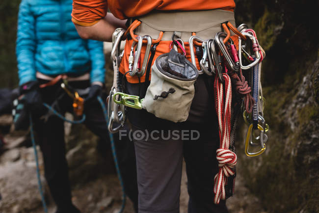 Пара з карабінером готується до сходження на скелю в лісі — стокове фото