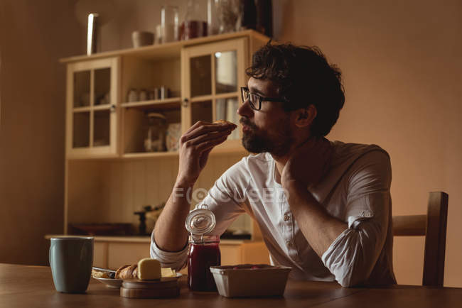 Homem atencioso tomando café da manhã na cozinha em casa — Fotografia de Stock