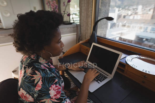Mulher cuidadosa usando laptop na mesa em casa . — Fotografia de Stock