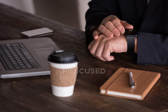 Mid section of businessman checking smart watch in creative office — Stock Photo