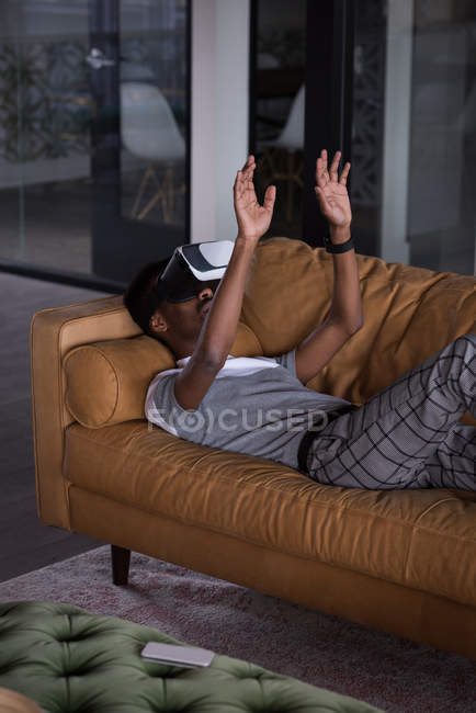 Office executive using Virtual reality headset on sofa in the office — Stock Photo