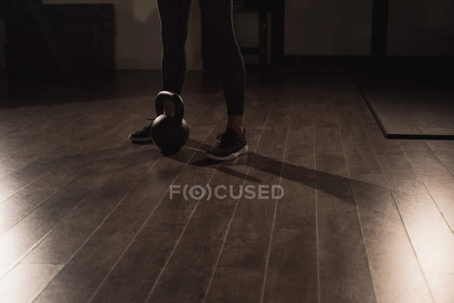 Unterteil einer Frau, die mit der Kettlebell im Fitnessstudio steht — Stockfoto