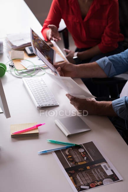 Коллеги обсуждают документы на рабочем столе в творческом офисе — стоковое фото