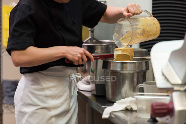 Mid section of chef pouring the ground mixture in a container — Stock Photo